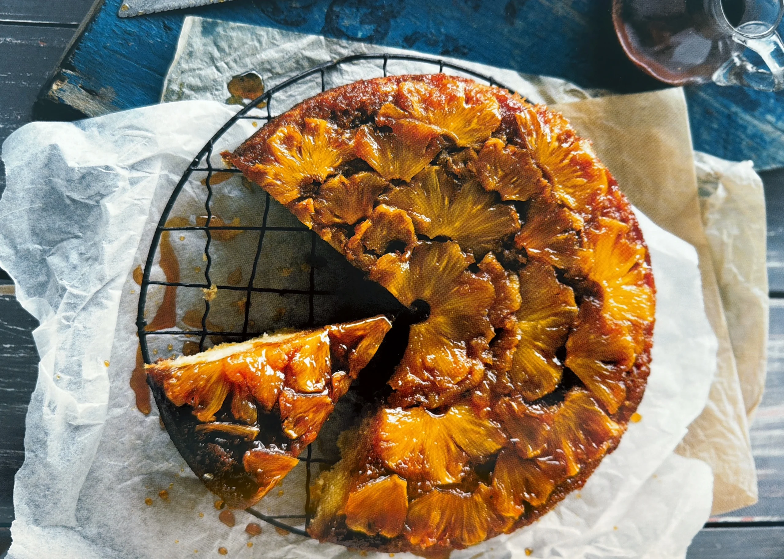 Pineapple upside-down cake with a slice cut out on a wire rack.
